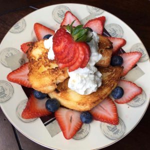 broiled angel food cake with strawberries and blueberries on a white plate with a black background
