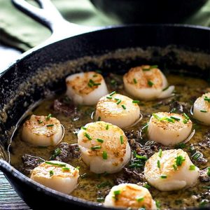 Pan Seared Scallops with Bacon Cream Sauce in a black skillet