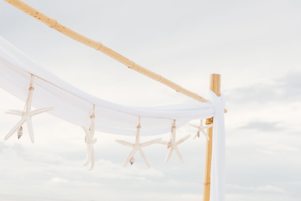 Elegant bamboo arch with starfish decor on a beach setting, exuding a serene coastal ambiance.