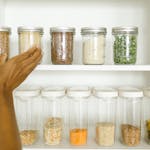A neat pantry shelf showing various grains stored in labeled glass and plastic containers, promoting kitchen organization.