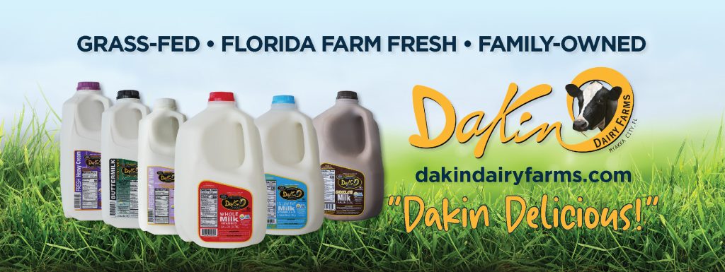 Assorted Dakin Dairy Farms milk and cream products displayed on fresh green grass with text: Grass-Fed, Florida Farm Fresh, Family-Owned – DakinDairyFarms.com – 'Dakin Delicious!'